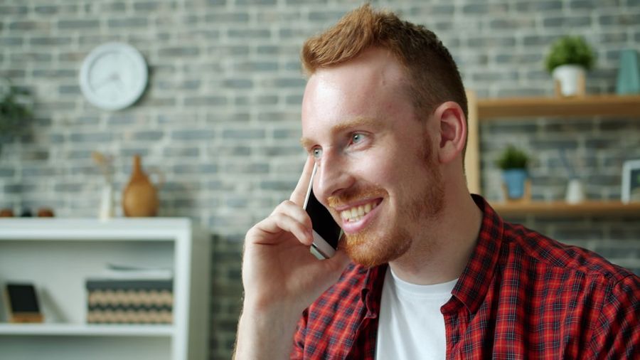 Smiling homeowner talking on the phone at home